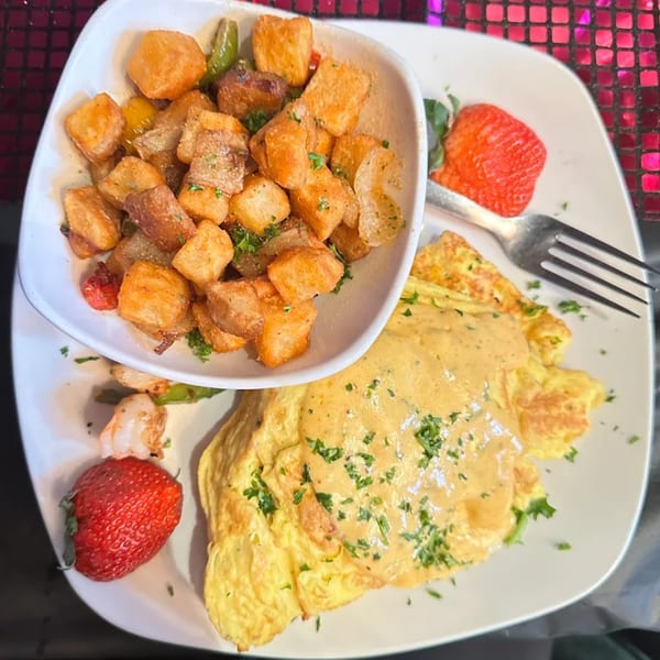 A Sugah Please brunch plate with a cheesy omelet, crispy home fries, and fresh strawberries.