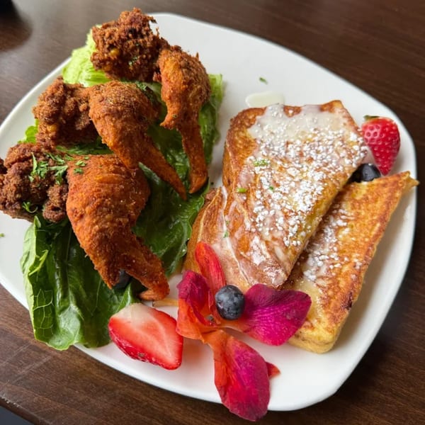 Sugah Please's chicken and waffles with french toast, strawberries, blueberries, and an orchid.